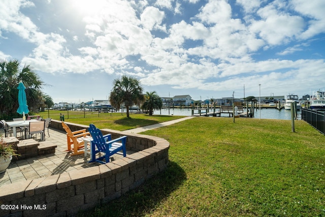 surrounding community with a dock, a yard, a water view, and a patio area