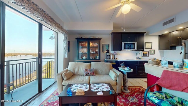 living room with a water view, ceiling fan, and light tile patterned flooring