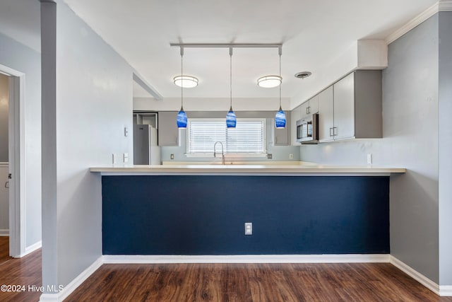 kitchen with appliances with stainless steel finishes, kitchen peninsula, and dark hardwood / wood-style floors