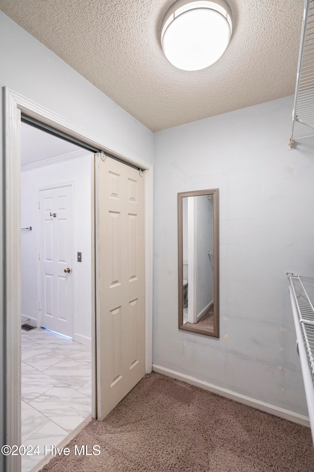 hallway featuring light carpet and a textured ceiling