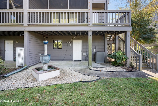 entrance to property with a patio, a deck, a lawn, and central air condition unit