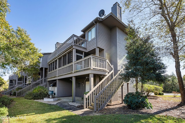 rear view of property with a wooden deck and a lawn