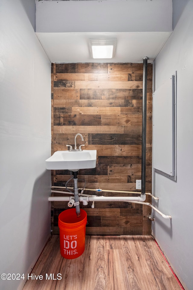 bathroom featuring wood walls, hardwood / wood-style floors, and sink