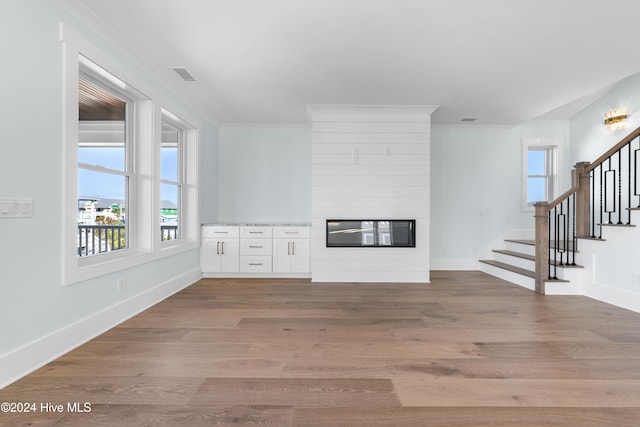 unfurnished living room featuring light hardwood / wood-style floors, crown molding, and a fireplace