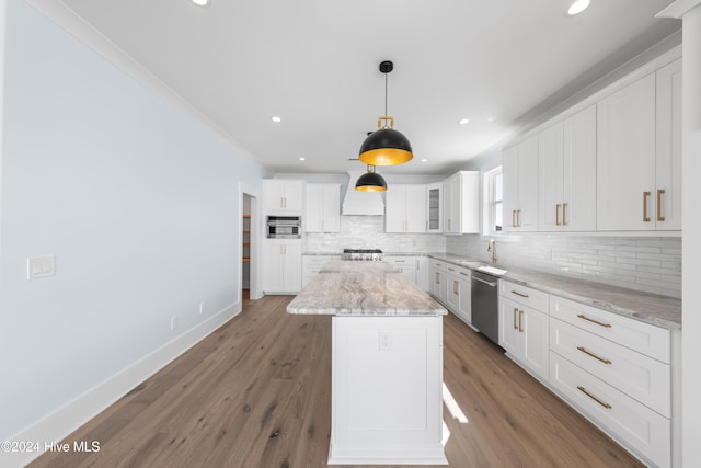 kitchen with appliances with stainless steel finishes, white cabinetry, light stone counters, and hardwood / wood-style floors