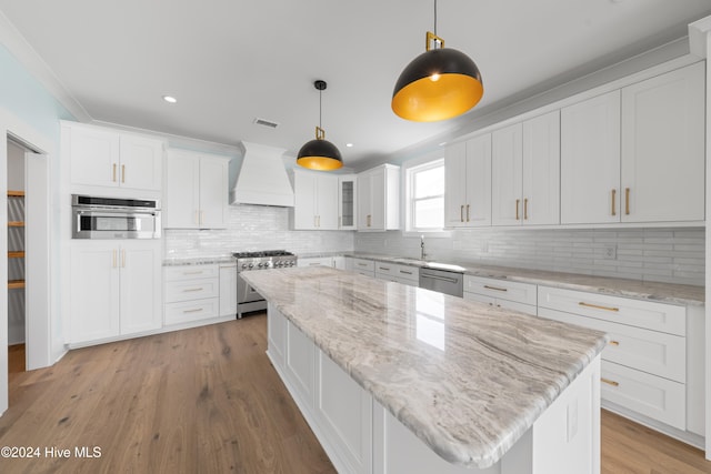 kitchen featuring decorative light fixtures, light wood-type flooring, white cabinetry, appliances with stainless steel finishes, and light stone counters