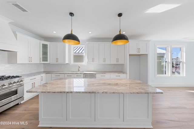 1405 Pinfish Ln, Carolina Beach, NC 28428 - kitchen with stainless steel appliances, a kitchen island, white cabinets, backsplash, and glass insert cabinets