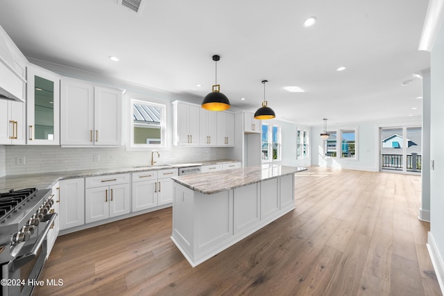1405 Pinfish Ln, Carolina Beach, NC 28428 - kitchen featuring stainless steel appliances, a sink, white cabinetry, backsplash, and wood finished floors