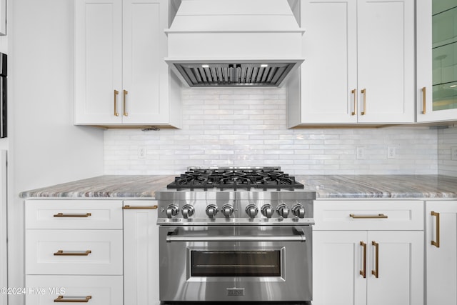 kitchen with custom exhaust hood, decorative backsplash, white cabinets, light stone countertops, and high end range