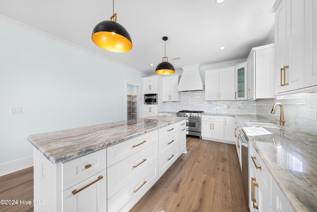 kitchen with appliances with stainless steel finishes, sink, a center island, white cabinetry, and premium range hood