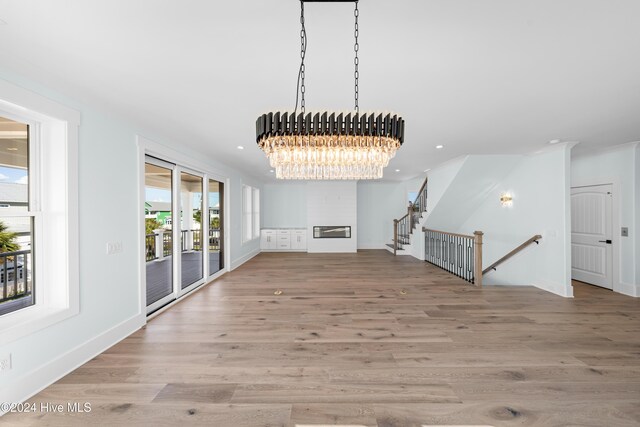 1405 Pinfish Ln, Carolina Beach, NC 28428 - unfurnished living room with wood finished floors, a chandelier, recessed lighting, a glass covered fireplace, and baseboards