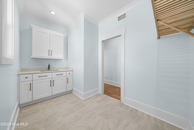 bar featuring crown molding, white cabinets, and sink