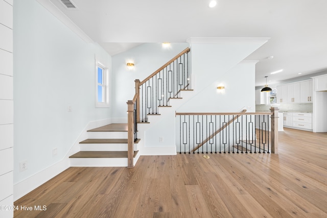 staircase with crown molding and hardwood / wood-style flooring