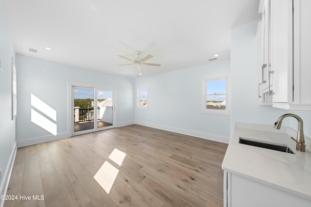 unfurnished living room featuring sink, light wood-type flooring, and ceiling fan