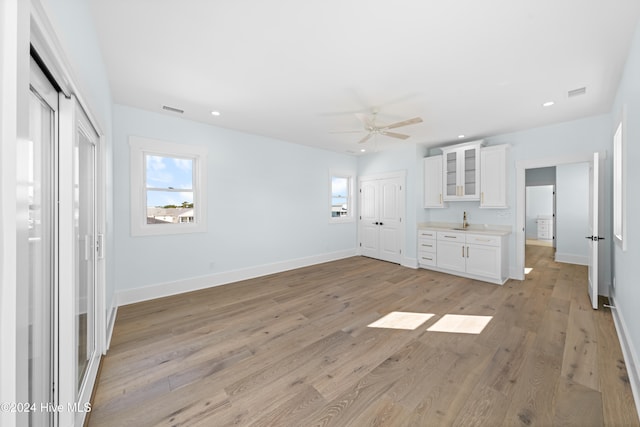 unfurnished bedroom featuring multiple closets, sink, light wood-type flooring, and ceiling fan