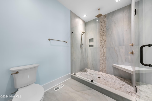 bathroom featuring a shower with door and toilet