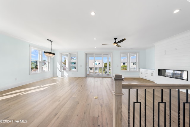 unfurnished living room with light hardwood / wood-style flooring and ceiling fan with notable chandelier