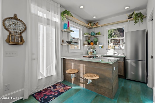 kitchen with kitchen peninsula, dark hardwood / wood-style floors, and stainless steel fridge