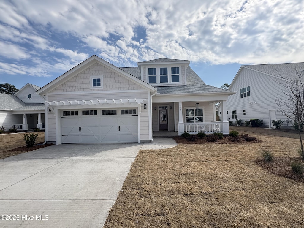 view of front of home with a porch, concrete driveway, a shingled roof, and an attached garage