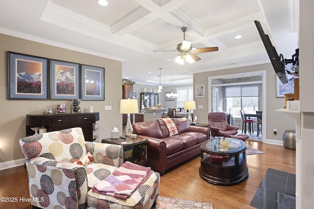 living room with light wood-type flooring, ornamental molding, coffered ceiling, ceiling fan with notable chandelier, and beamed ceiling