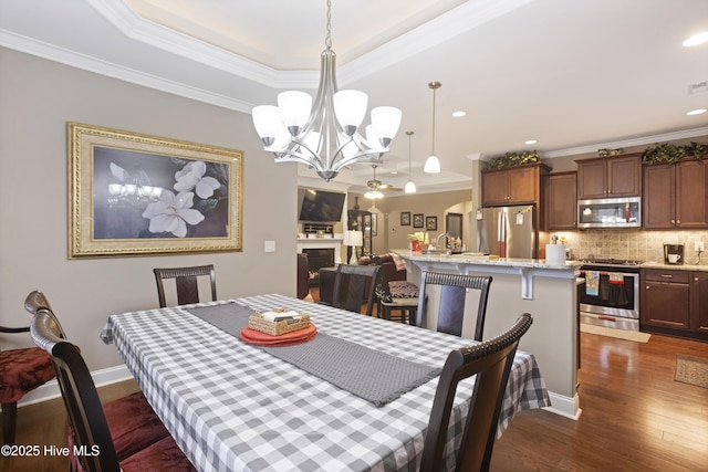 dining space featuring a notable chandelier, dark hardwood / wood-style flooring, a raised ceiling, and crown molding