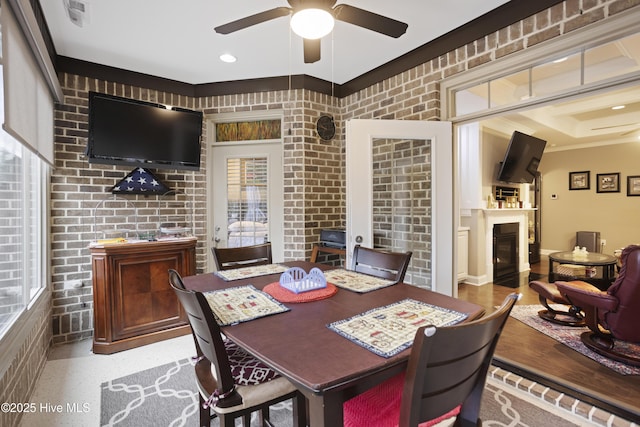 dining area featuring ceiling fan, a healthy amount of sunlight, and brick wall