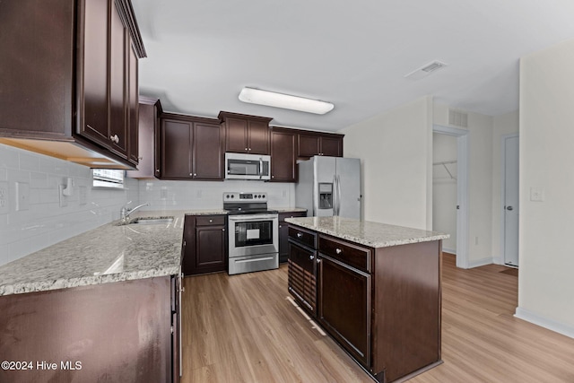 kitchen with light hardwood / wood-style flooring, a kitchen island, sink, and stainless steel appliances