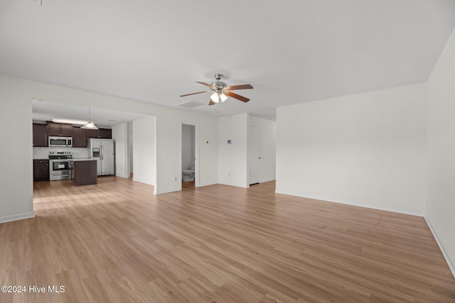 unfurnished living room with a ceiling fan, visible vents, light wood-style floors, and baseboards