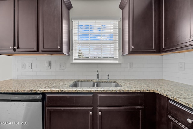 kitchen featuring light stone counters, backsplash, dark brown cabinetry, sink, and stainless steel dishwasher