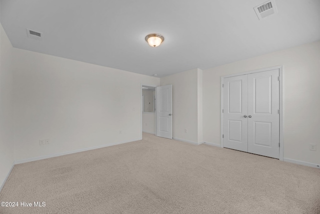 unfurnished bedroom featuring light colored carpet and a closet