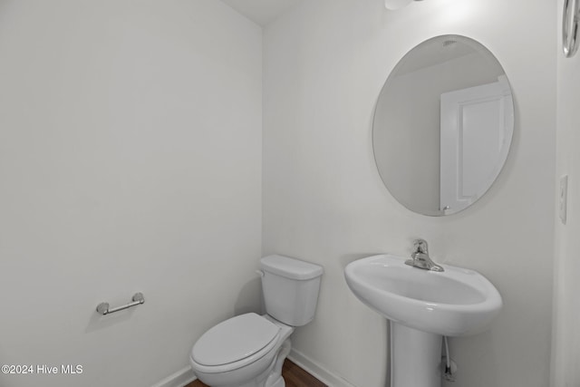 half bathroom with baseboards and toilet