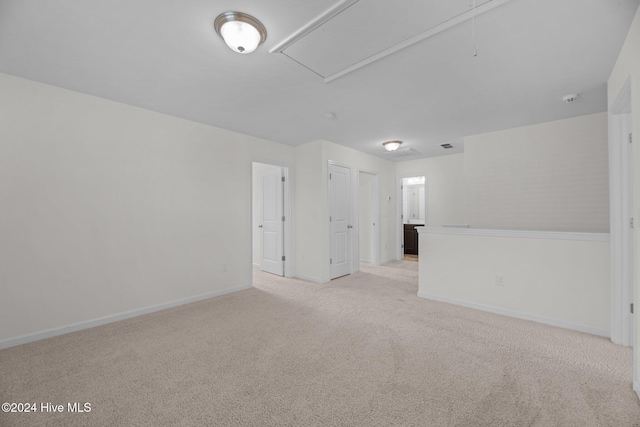 unfurnished room featuring attic access, baseboards, and light carpet