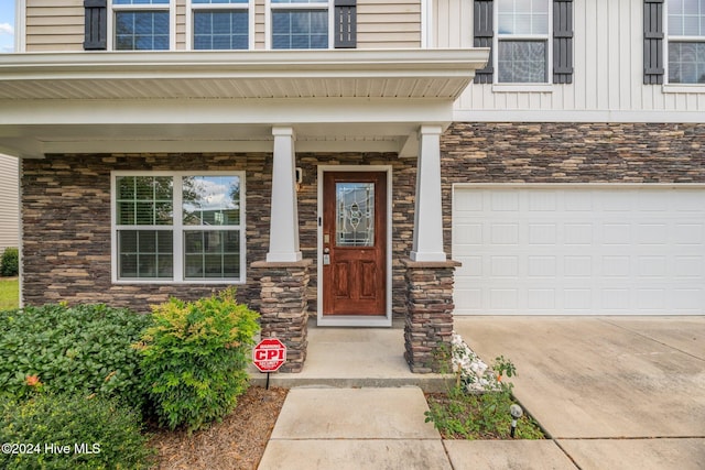 414 Louisia Mae Way, New Bern, NC 28560 - doorway to property featuring stone siding, a garage, driveway, board and batten siding, and a porch