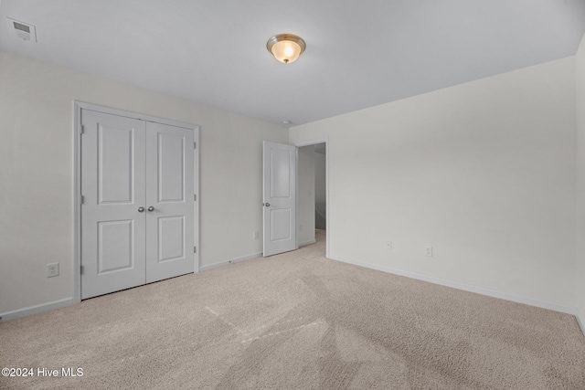 unfurnished bedroom with a closet and light carpet