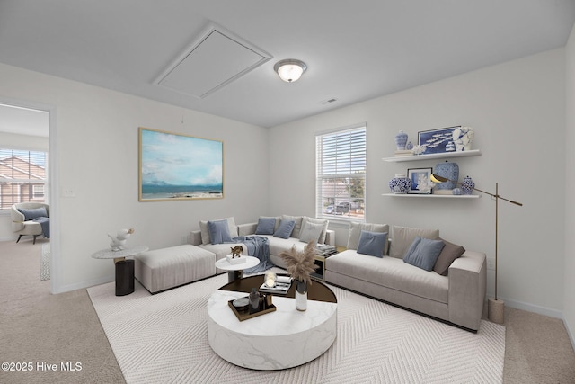 carpeted living area with attic access and baseboards