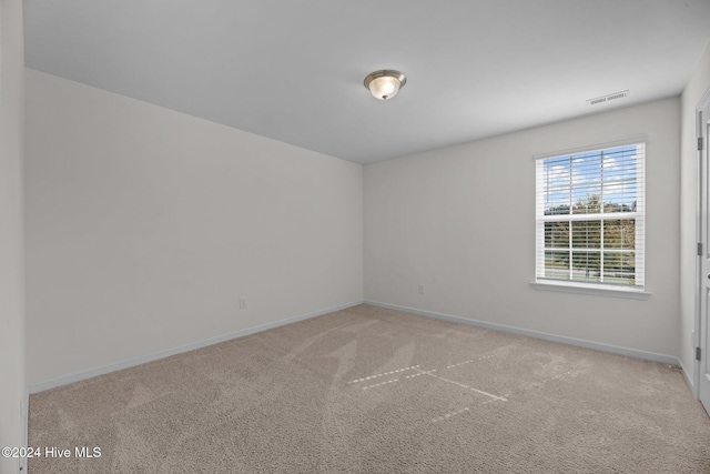 spare room with visible vents, light carpet, and baseboards