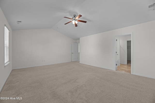 empty room with vaulted ceiling, light colored carpet, and ceiling fan