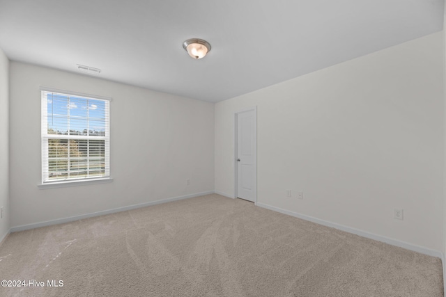 carpeted spare room with visible vents and baseboards