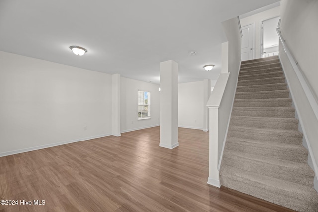 below grade area with stairway, wood finished floors, and baseboards