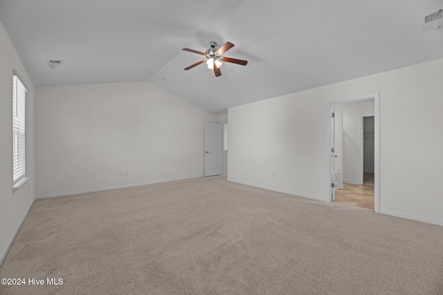 spare room featuring visible vents, baseboards, light colored carpet, ceiling fan, and vaulted ceiling