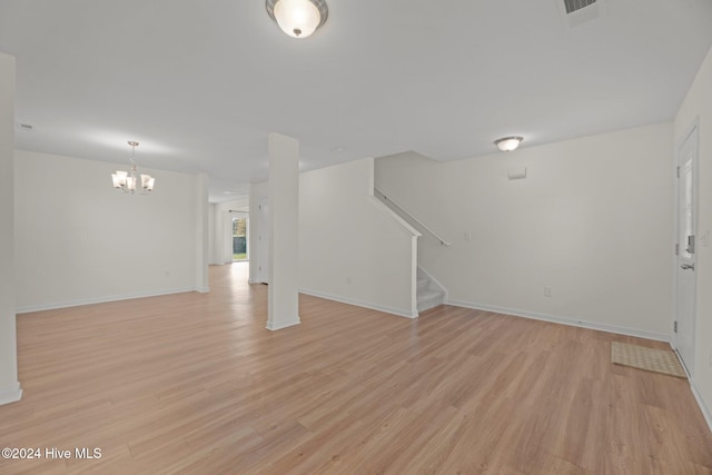 unfurnished living room with a notable chandelier and light hardwood / wood-style flooring