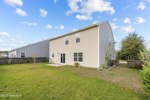 back of house featuring a patio area, a lawn, a hot tub, and fence