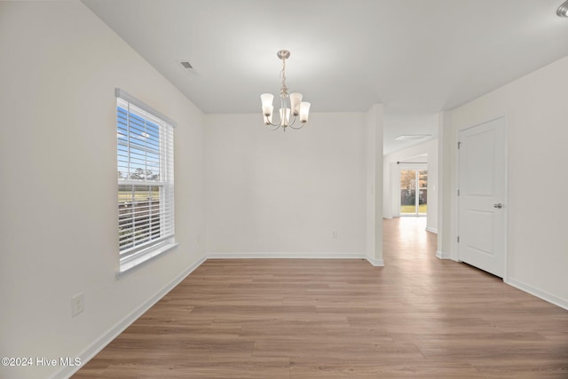 empty room featuring light hardwood / wood-style flooring and a notable chandelier