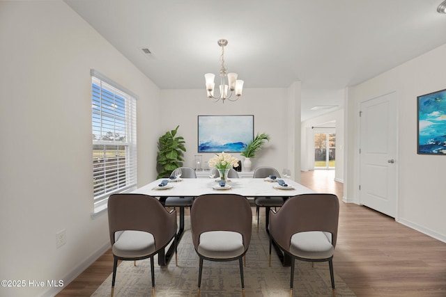 dining space with visible vents, baseboards, an inviting chandelier, and wood finished floors