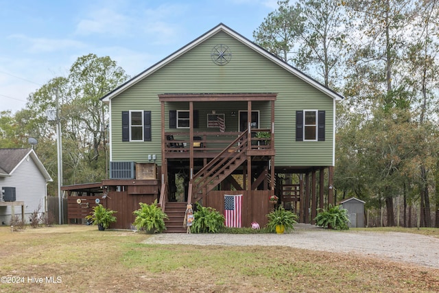 view of front facade featuring a storage unit, a wooden deck, and a front lawn