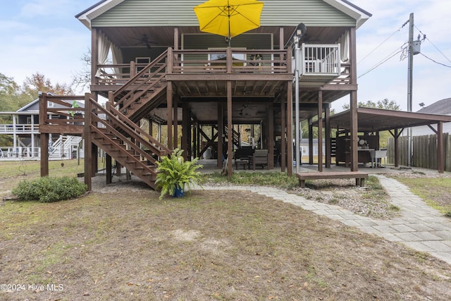 back of house featuring ceiling fan, a carport, and a deck