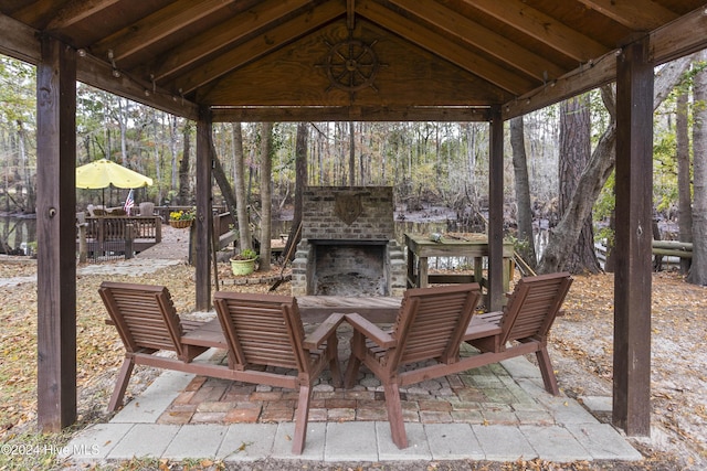 view of patio featuring a gazebo and an outdoor brick fireplace