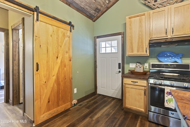 kitchen featuring gas range, butcher block counters, a barn door, dark hardwood / wood-style flooring, and vaulted ceiling