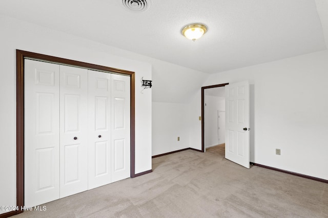 unfurnished bedroom featuring a closet, vaulted ceiling, and light carpet