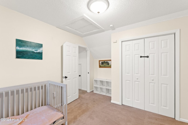 carpeted bedroom featuring a closet, vaulted ceiling, and a textured ceiling